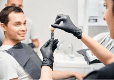 Diş hekimi hastasına “implant ağrılı mı” sorusunu açıklarken implant modelini gösteriyor.